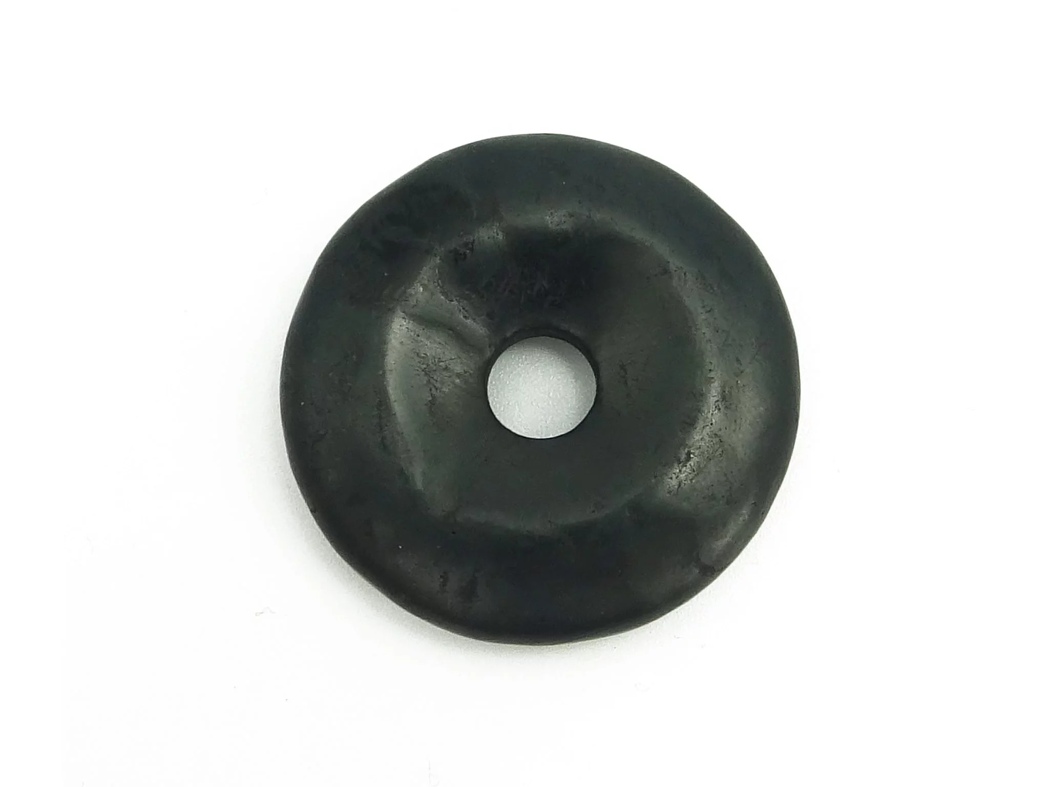 Pendentif donut en shungite noir en vue détaillée de la surface naturelle sur fond blanc