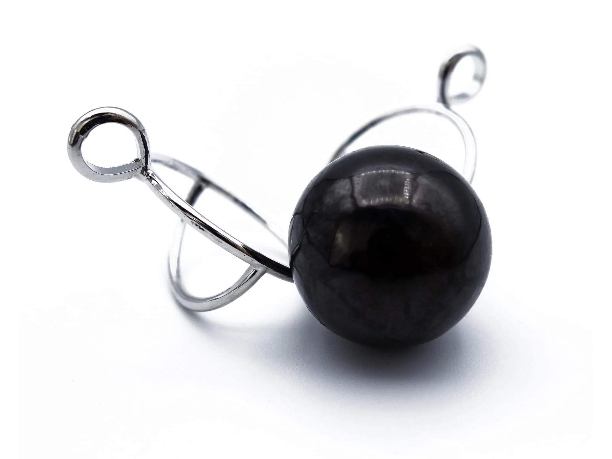 Pendentif en pierre de shungite avec monture de cage argentée ouverte à côté de la boule noire