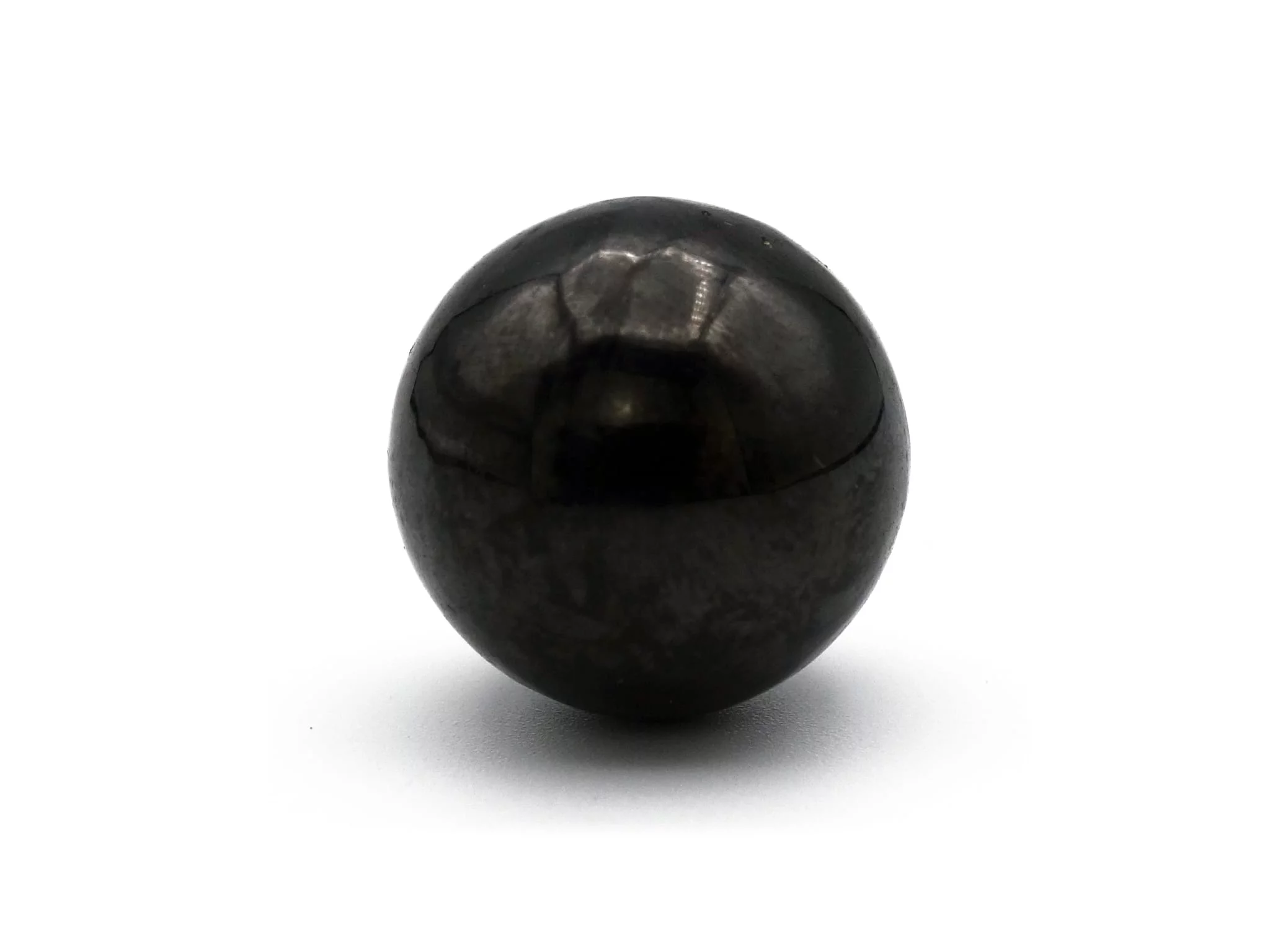 Pendentif en pierre de shungite sous forme de boule de pierre noire brillante en gros plan sur fond blanc