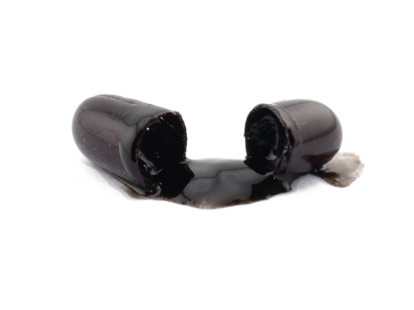 Shilajit softgel capsules opened with visible dark content on a white background