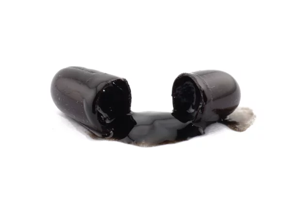 Shilajit Softgel Kapseln geöffnet mit sichtbarem dunklem Inhalt auf weissem Hintergrund