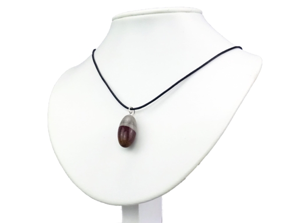 Shiva Lingam gemstone pendant worn on black necklace displayed on white bust stand