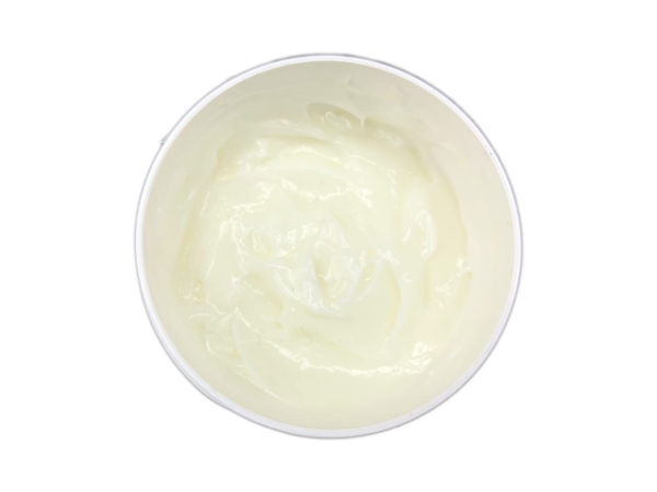 Crème de soin à l’herbe du tigre sous forme de crème brillante et jaunâtre dans un pot ouvert, vue de dessus