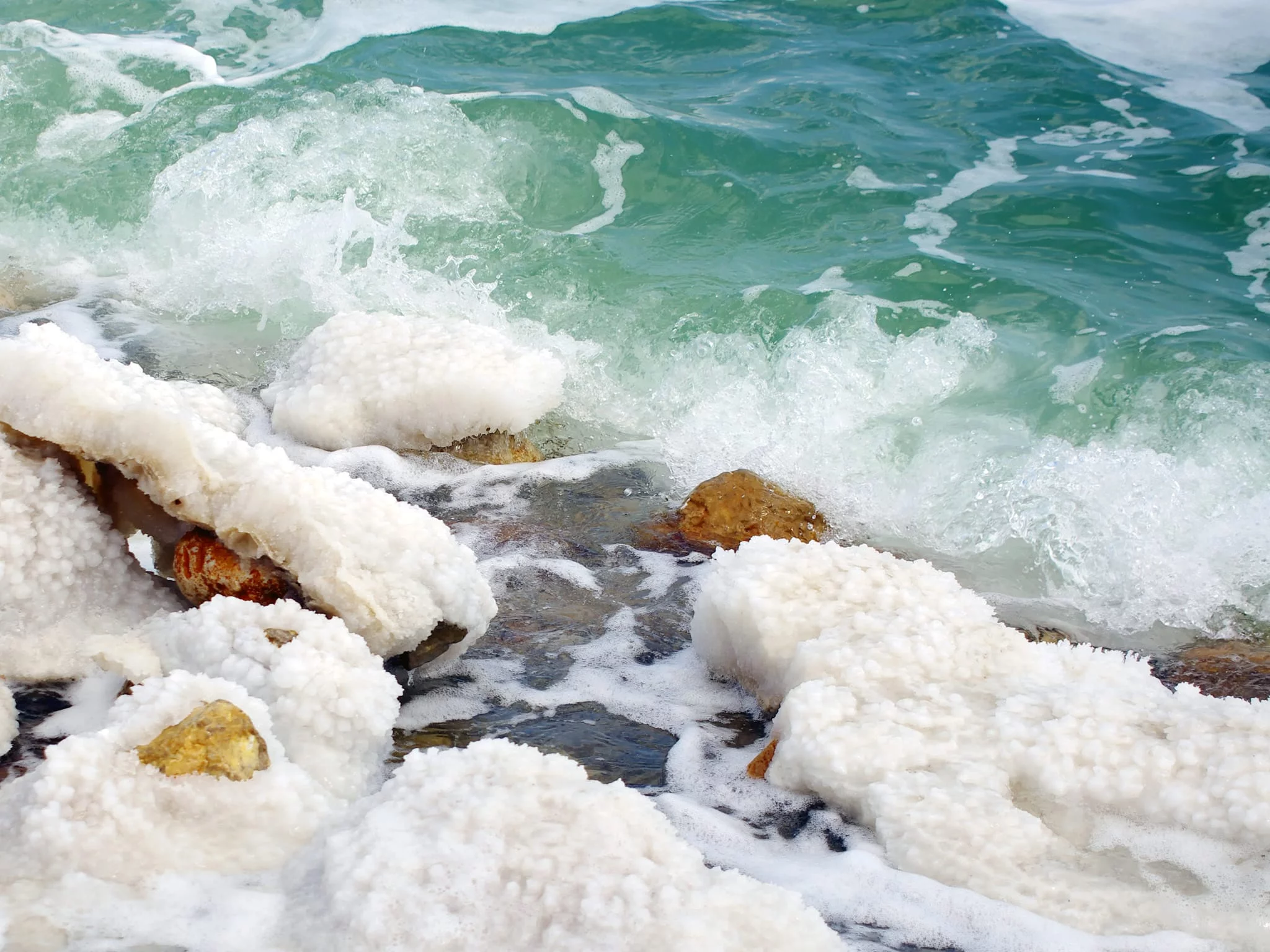 Totes Meer Salz Creme mit weissen Salzkristallen auf Felsen am türkisfarbenen Wasser