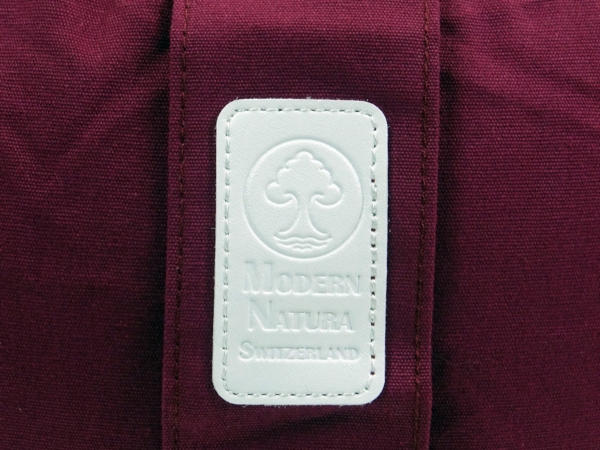 Coussin de yoga Vino avec vue détaillée de l’étiquette blanche Modern Natura sur tissu bordeaux