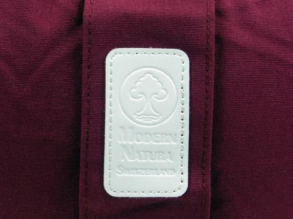 Yogakissen Vino mit Detailansicht des weissen Modern Natura Markenlabels auf weinrotem Stoff